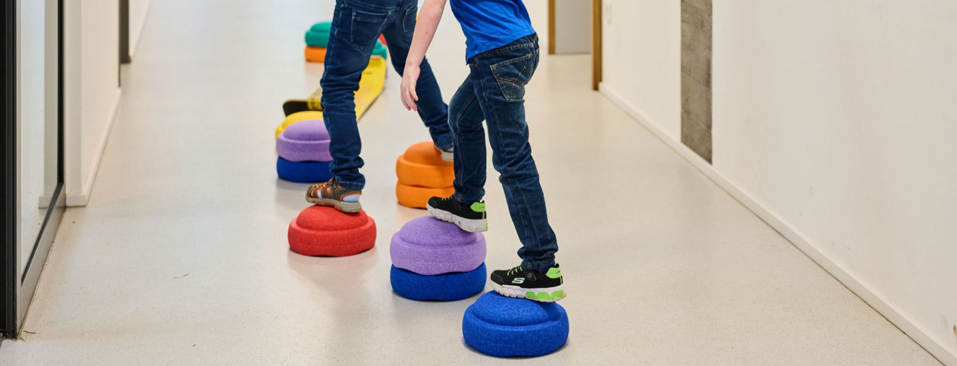 Zwei Schüler balancieren auf halbrunden Bausteinen.