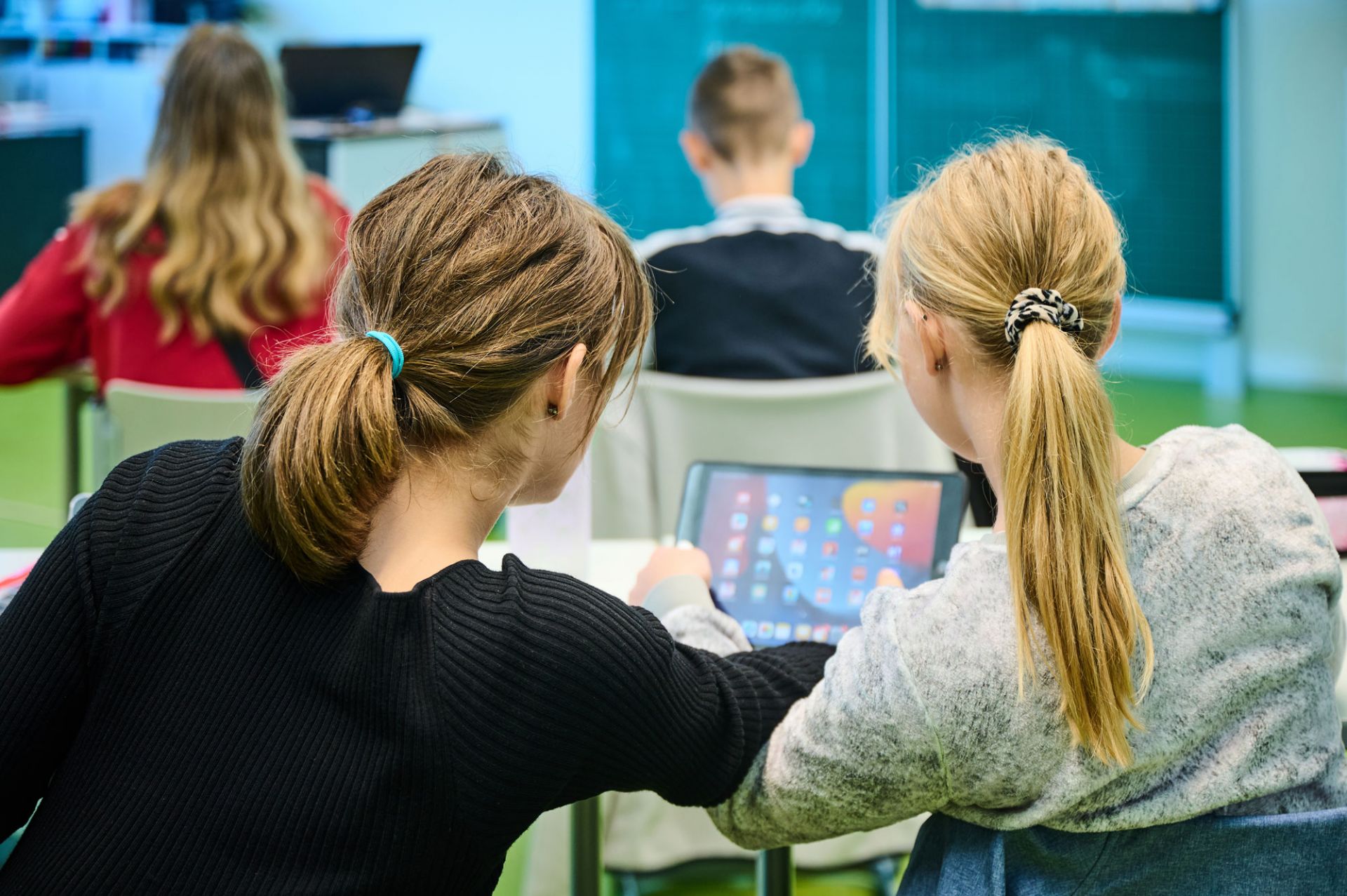 Zwei Schülerinnen blicken zusammen in ein Tablet.