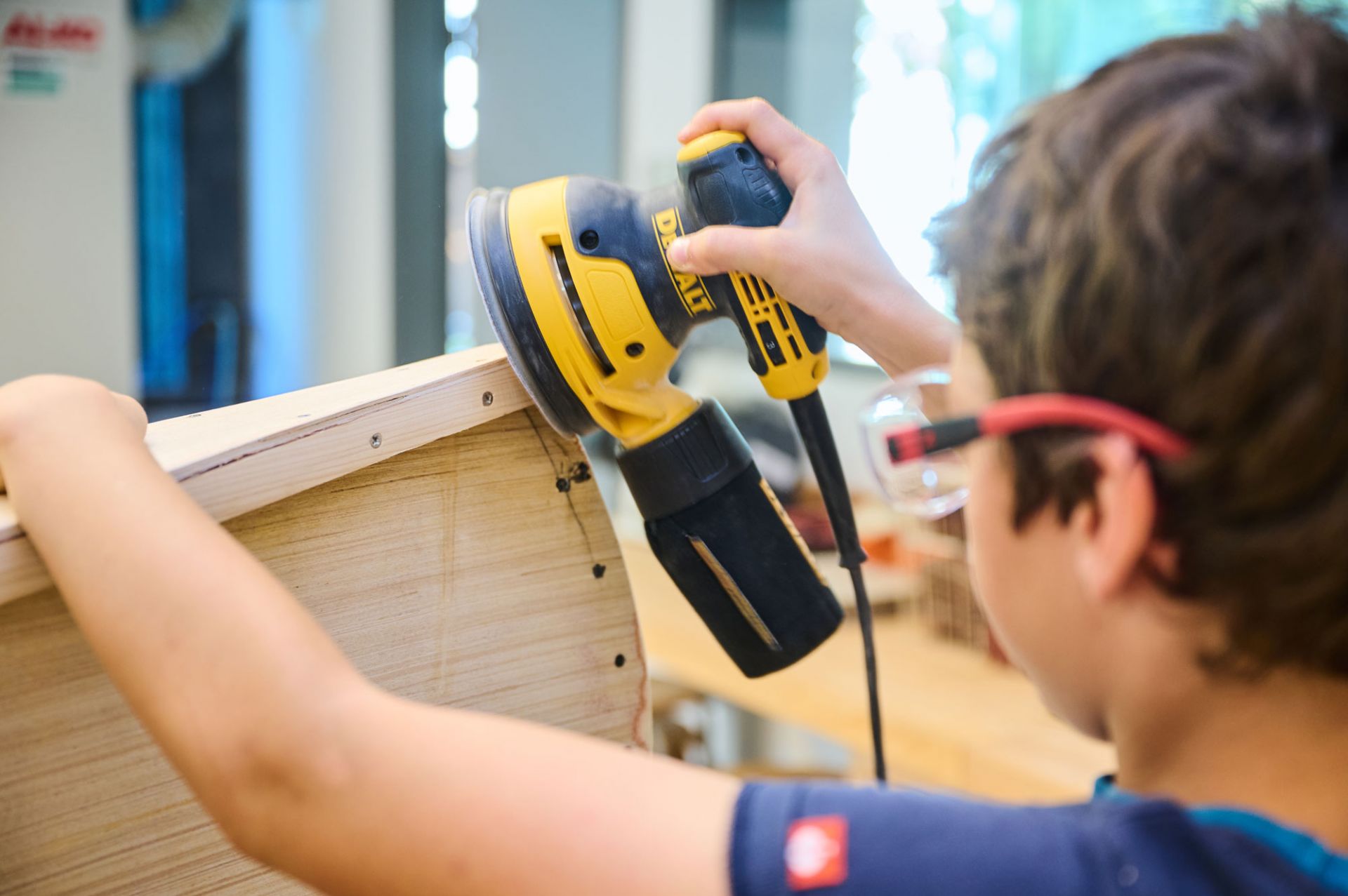 Schüler schleift mit einer Maschine Holz
